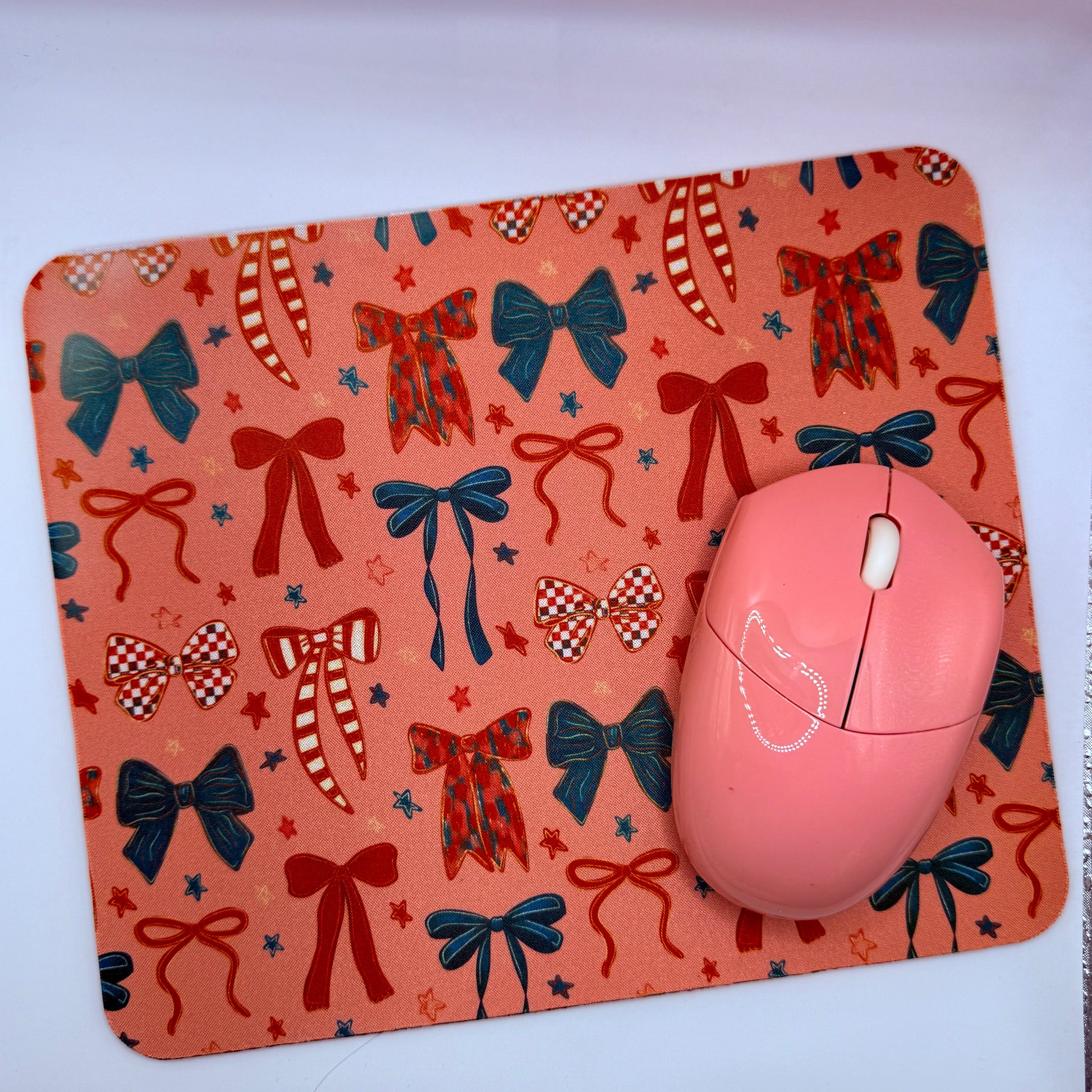 Pink mouse on a decorative mouse pad with bow patterns