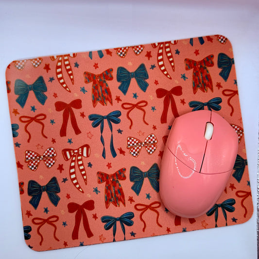 Pink mouse on a decorative mouse pad with bow patterns