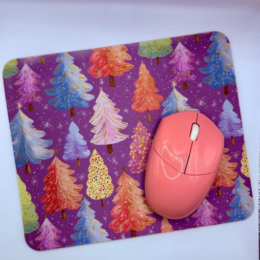 Pink computer mouse on a purple mouse pad with colorful tree design